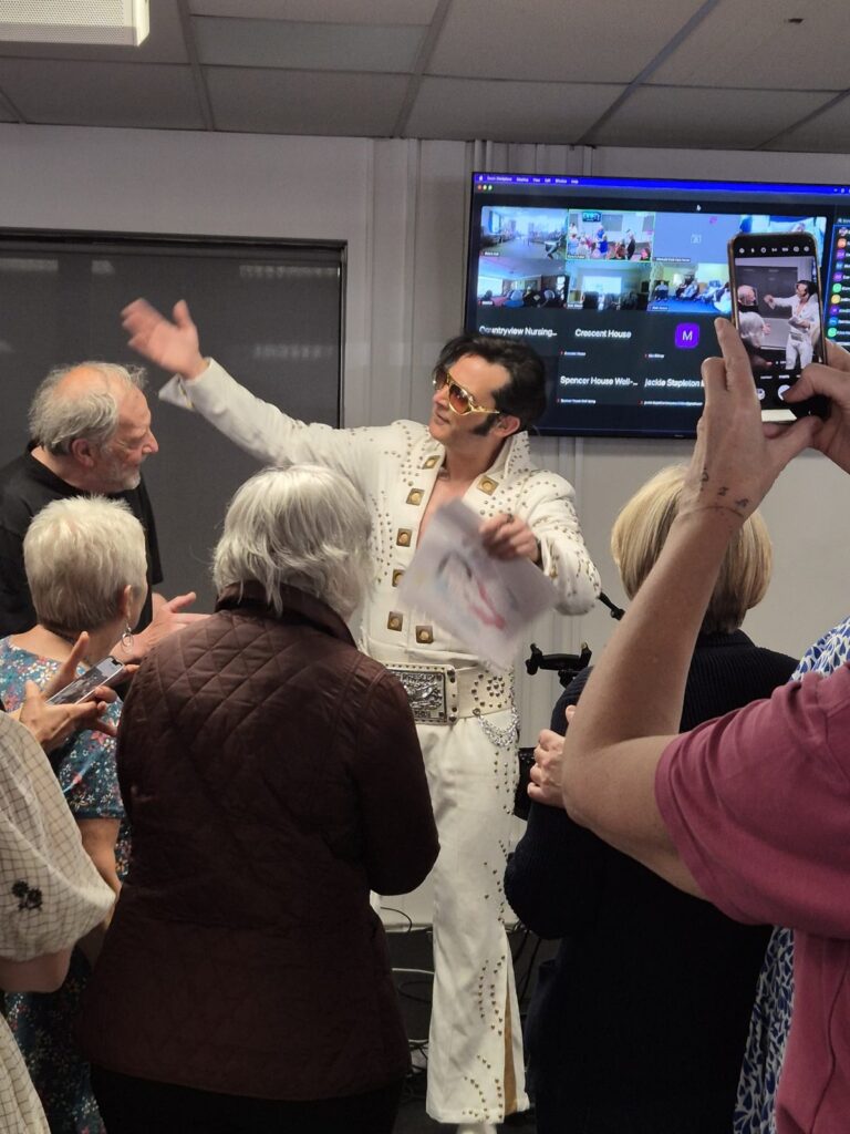 DSO members dancing with their arms in the air as an Elvis tribute act performs