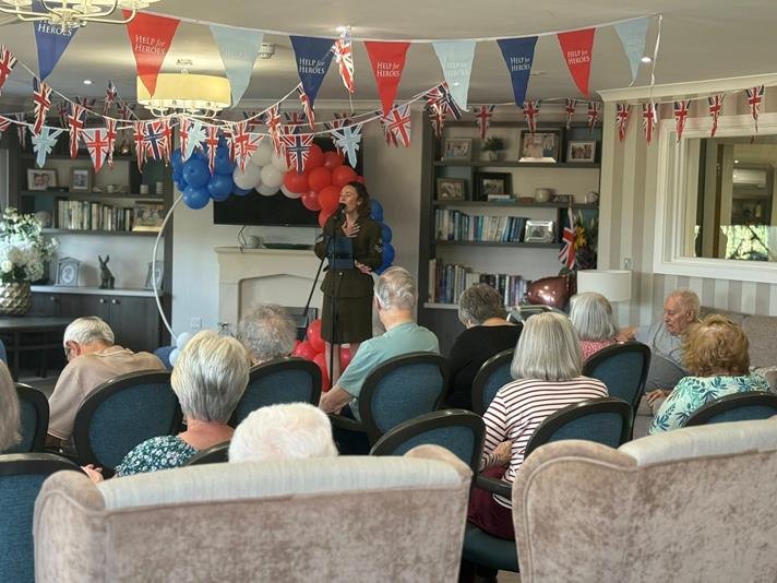 Residents seated beneath red, white and blue bunting at Glenvale Park Care Home listening to a singer