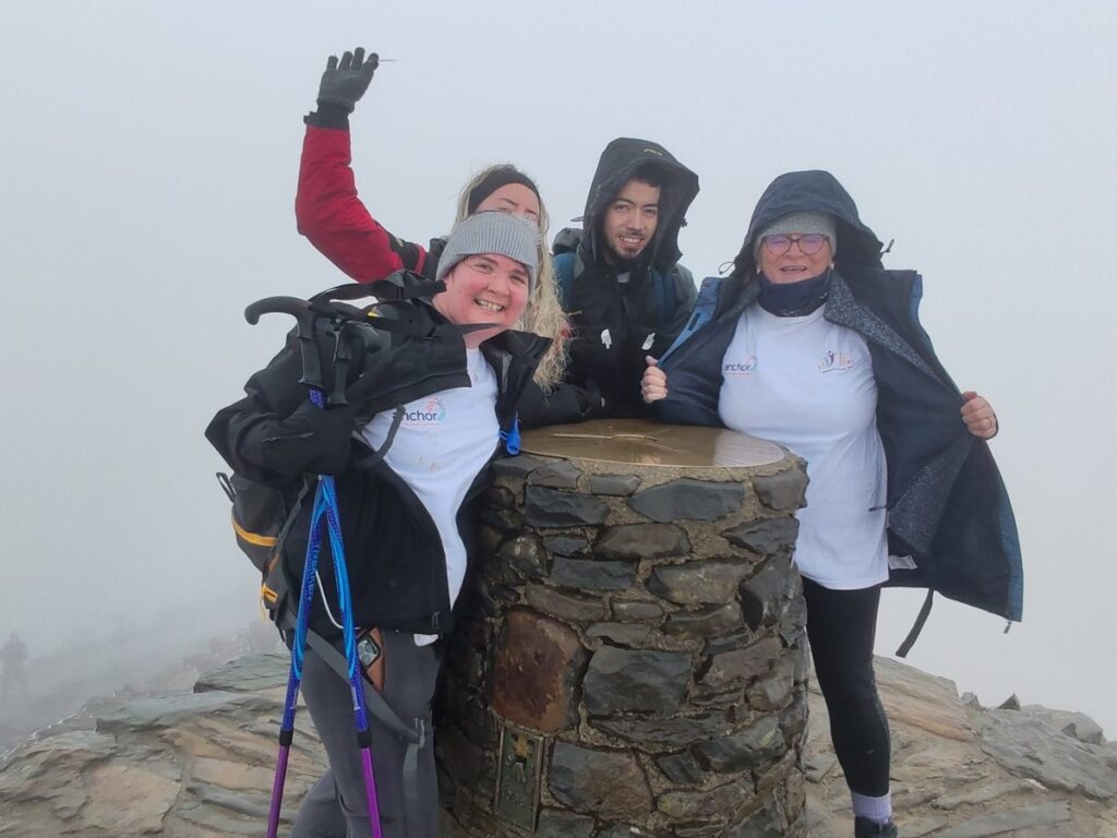 Three fundraisers at the misty summit trig point of Snowdon after climbing for Dementia Sings Out
