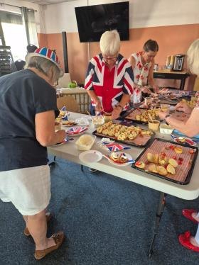 Volunteers in Union Jack outfits serving scones, cream and cakes at the DSO VE Day session