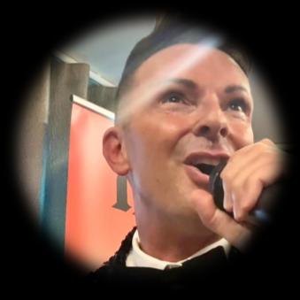Simon from Sunset Magic singing into a handheld microphone