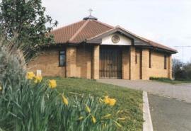 The Abbey Centre Chapel in East Hunsbury, a low brick building with daffodils in front